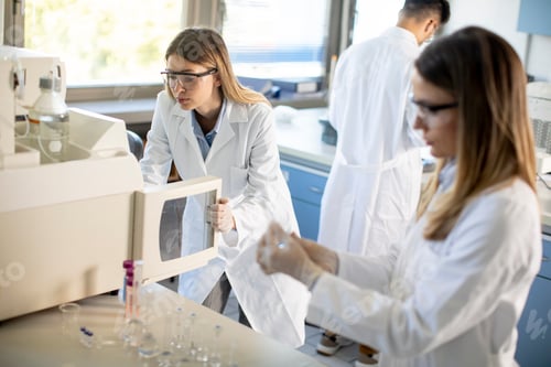 Preview: Young female scientists in a white lab coat putting