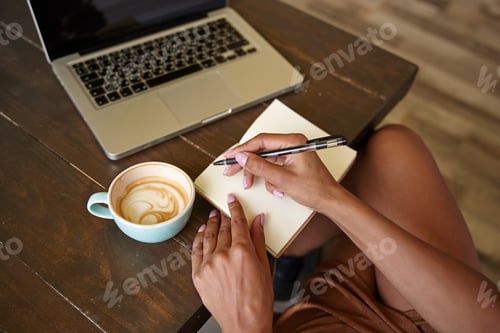 Preview: Indoor close-up of wooden countertop with laptop on it, freelancer female working in public place