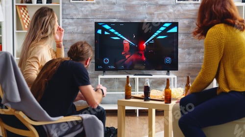 Preview: Back view of blonde woman playing shooter games