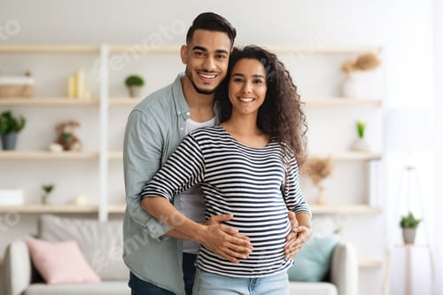 Preview: Happy middle-eastern man hugging his beautiful pregnant wife, posing together
