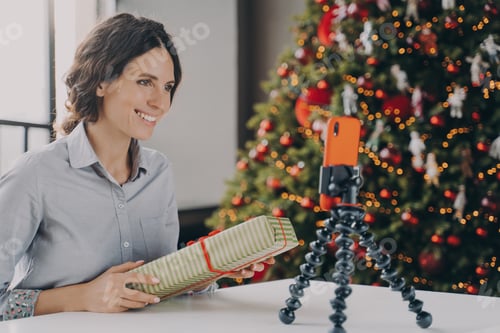 Preview: Smiling positive female blogger recording video tutorial about tips for wrapping Christmas presents
