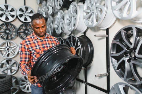 Preview: African american Car mechanic holding car rims ready to mount the wheels in workshop