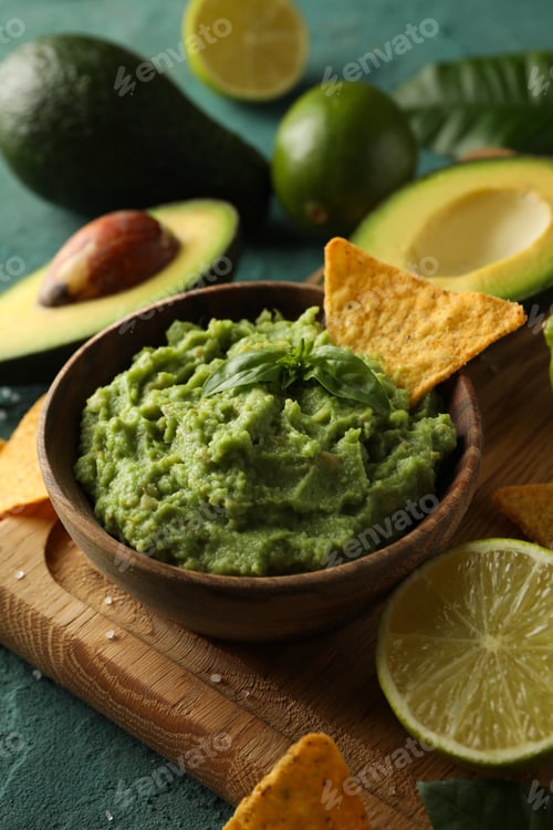 Preview: Concept of tasty eating with bowl of guacamole on green textured background