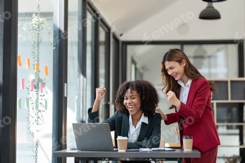 Preview: Young Asian and African businesswoman African woman relaxing with coffee mug while brainstorming inv