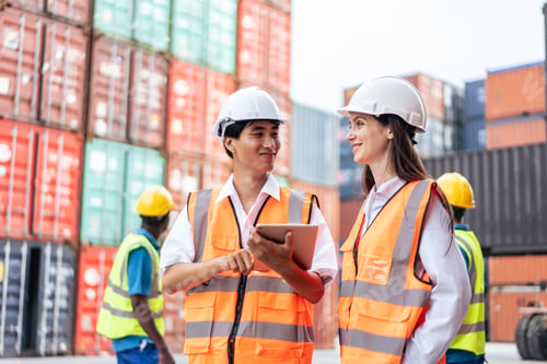 Preview: Caucasian business woman and Asian man working in container terminal.