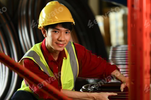 Preview: Man worker wearing hard hat carrying plastic tube in warehouse.