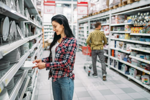 Preview: Young woman choosing plates in supermarket