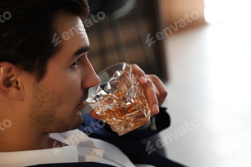 Preview: Young man with glass of whiskey indoors