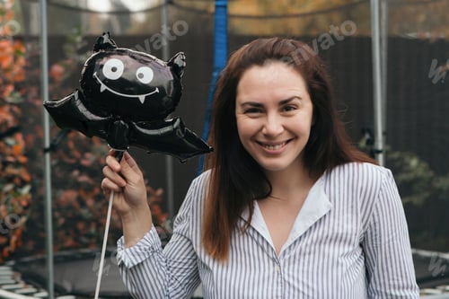 Preview: Young woman with Halloween balloon outdoors