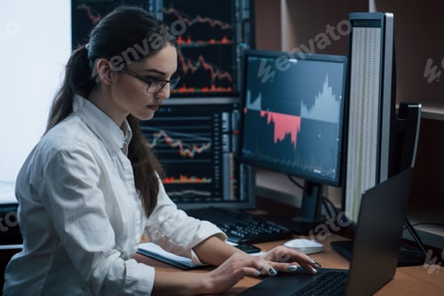 Preview: Woman working online in the office with multiple computer screens in index charts