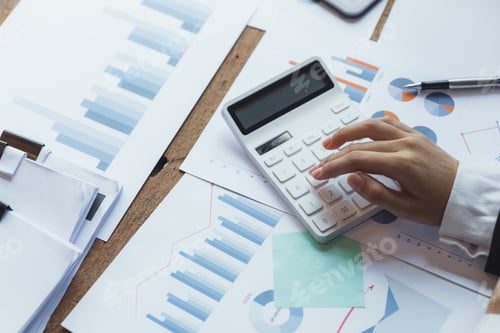 Preview: Businessman using a calculator to calculate numbers on a company's financial documents.