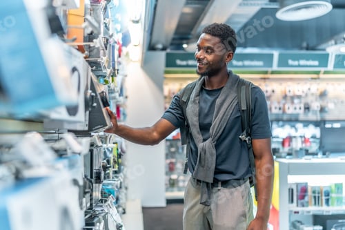 Preview: African man checking headphones in electronics store