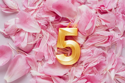 Preview: Number one golden celebration birthday candle on yellow and blue confetti Background.