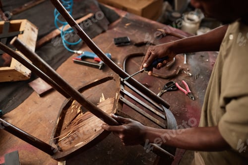 Preview: Close up of black man in furniture restoration workshop fixing wooden chair
