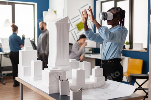 Preview: Architect working with virtual reality goggles to look at white foam maquette