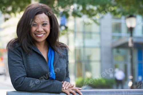 Preview: Business woman outdoors, in a grey suit with a bright blue shirt.