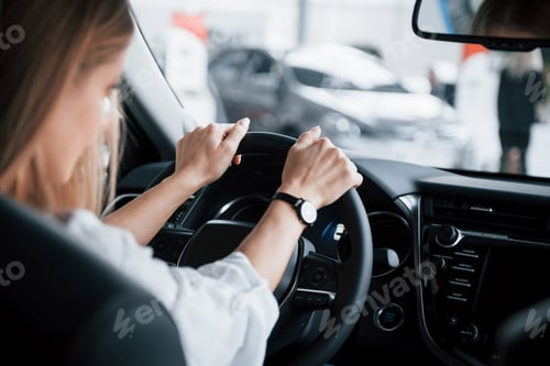 Preview: Are we going or not. Beautiful blonde girl sitting in the new car with modern black interior