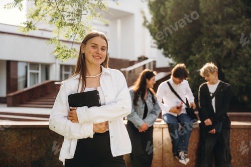 Preview: Girl is standing in front of her friends. Group of students are near university together