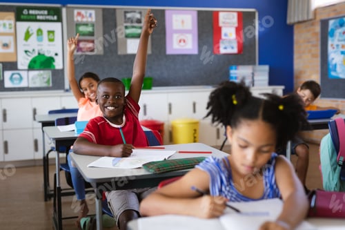 Preview: African american boy and girl raising their hands while sitting in the class at elementary school