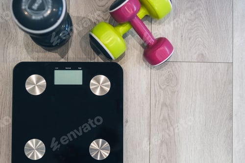 Preview: Dumbbells and modern scales on the floor in a room