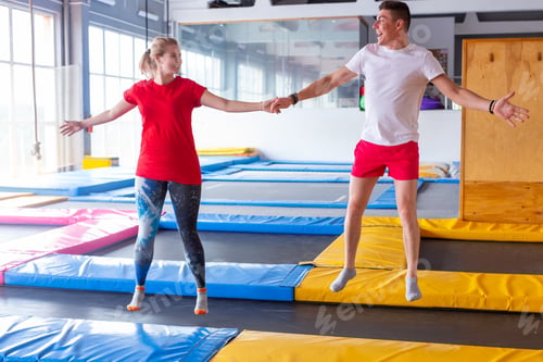 Preview: Fitness, fun, leisure and sport activity concept - Funny happy man and woman jumping on a trampoline