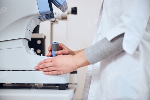 Preview: Focused image of experienced doctor looking lens in patient eyes with special machine