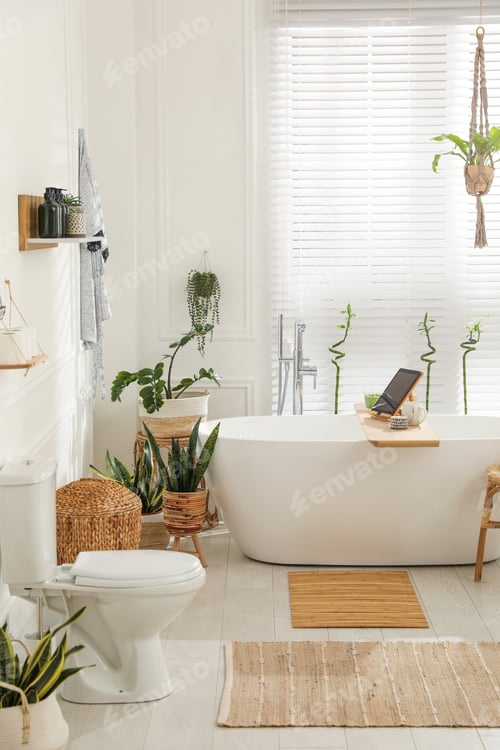 Preview: Stylish white tub and green houseplants in bathroom. Interior design