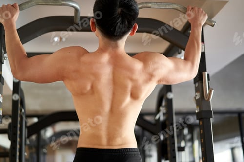 Preview: Asian man pulling up in a training gym
