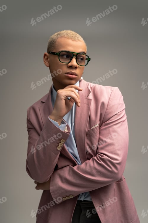 Preview: Stylish man exuding confidence in a soft pink blazer and fashionable glasses