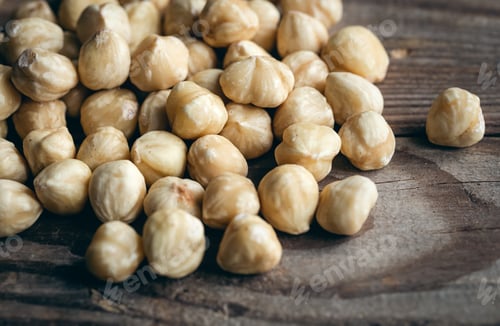 Preview: Heap of roasted hazelnuts close-up on a wooden background.