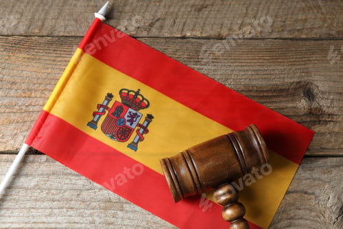 Preview: Judge's gavel and flag of Spain on wooden table, top view