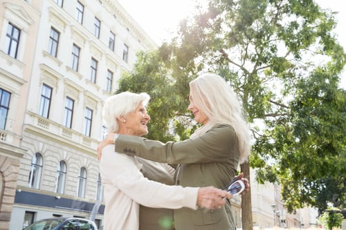 Preview: Mother and daughter hugging in street, smiling