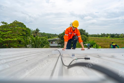 Preview: Technician in safety uniform and helmet kneeling on a rooftop