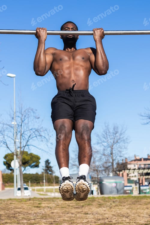 Preview: Strong black sportsman working out on bar in town