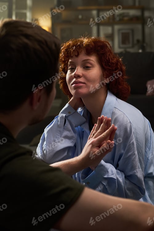 Preview: Young Woman Smiling While Touching Hands with Young Man Indoors