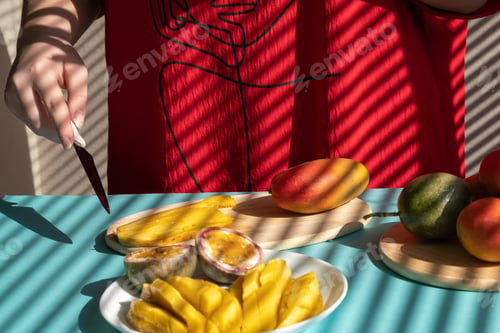 Preview: female hands cut mango and passion fruit, fruit breakfast