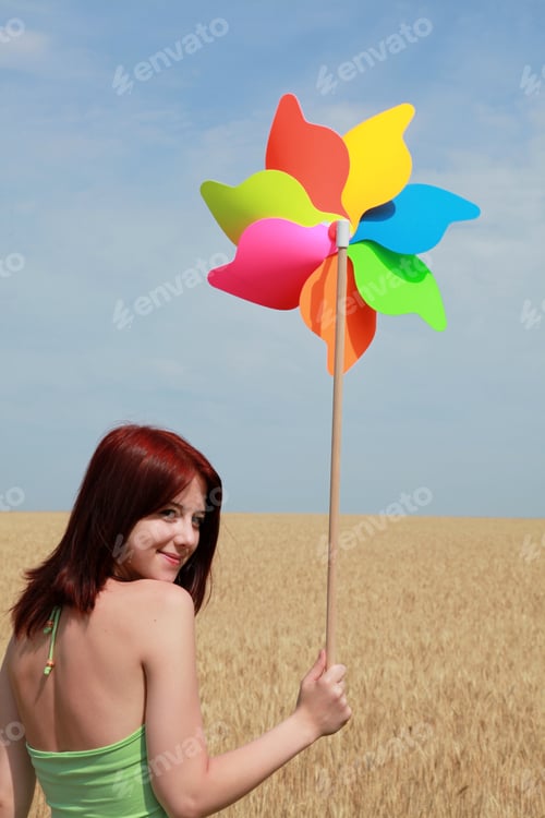 Preview: Girl with wind turbine at wheat field