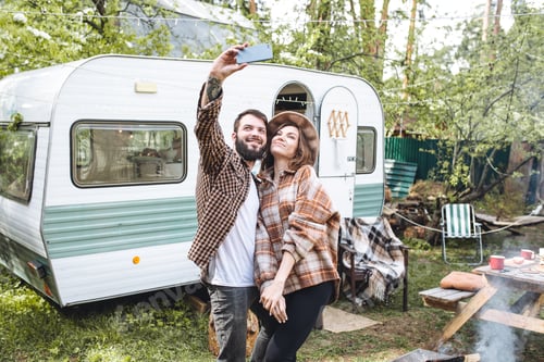 Preview: Couple taking a selfie outdoors near camper