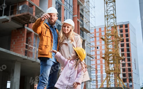 Preview: Happy family with apartment keys standing at construction site.