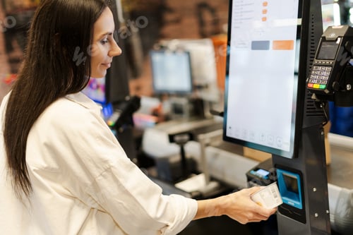 Preview: Customer using self-checkout kiosk scanning groceries in supermarket