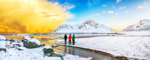 Preview: Group of tourist looking fabulous winter scenery on Skagsanden beach with illuminated clouds