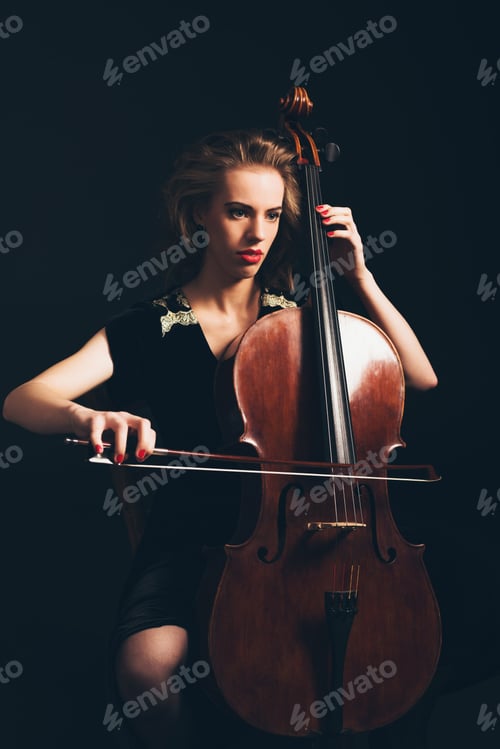 Preview: Young Woman Playing The Cello In A Classical Concert Or Recital Sitting In The Darkness With A