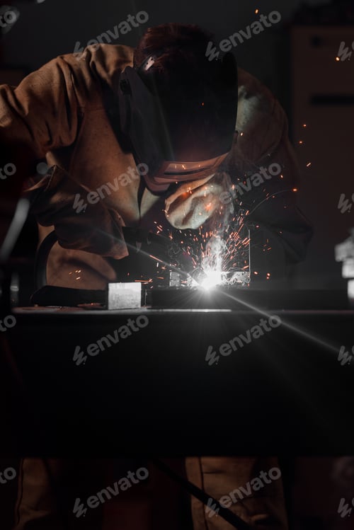 Preview: front view of welder in protection mask working with metal at factory