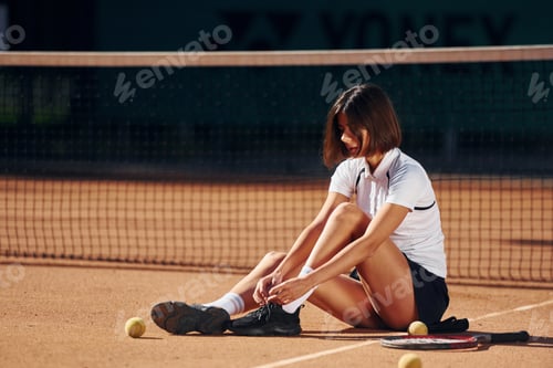 Preview: In white shirt and black skirt. Female tennis player is on the court at daytime