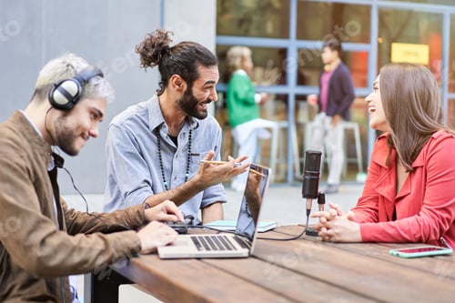 Preview: Young man interviewing a woman in a casual radio studio outdoors.