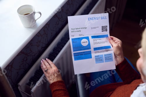 Preview: Close Up Of Senior Woman In Wheelchair With Energy Bill By Radiator In Cost Of Living Energy Crisis