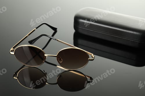 Preview: Stylish sunglasses and case on grey mirror surface, closeup