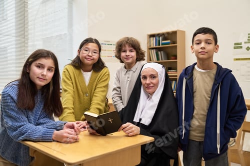 Preview: Caucasian Nun Teaching Diverse Children in Classroom Setting Holding Bible