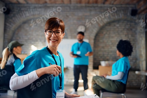 Preview: Happy woman volunteering at humanitarian aid center and looking at camera.