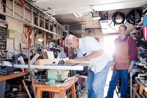Preview: Senior men sawing woodblock in carpentry workshop